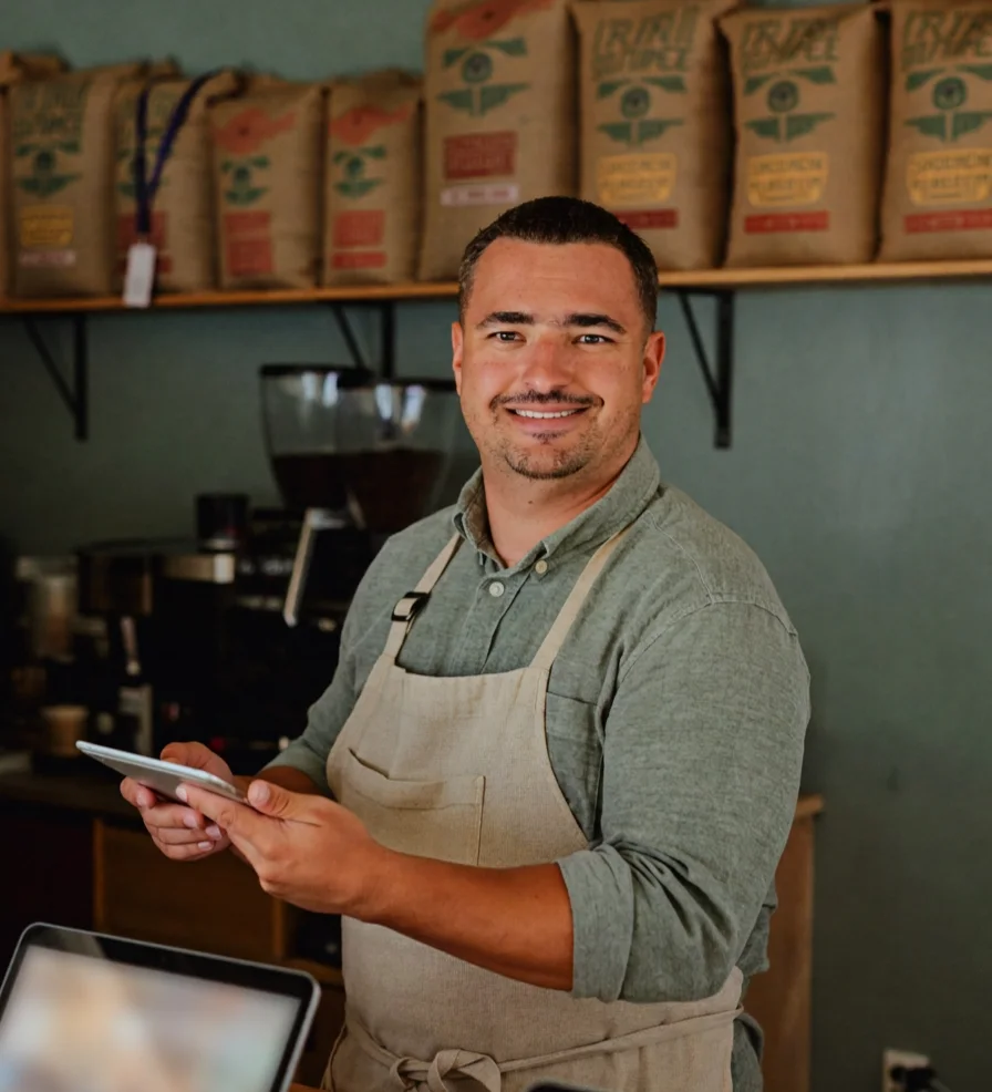 A coffee roastery owner holding a tablet behind his counter