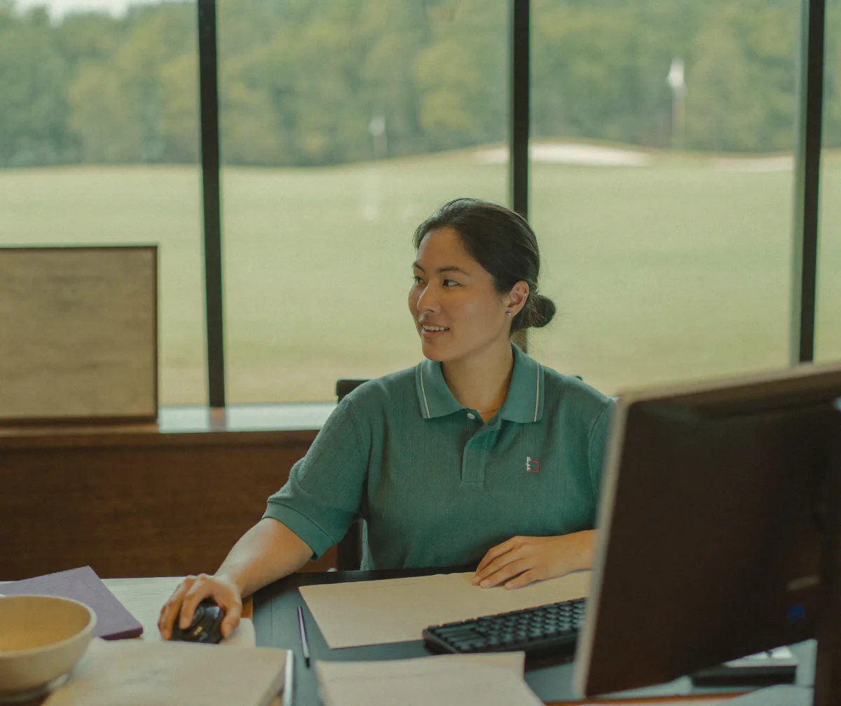 A golf course controller working at her desk overlooking the course