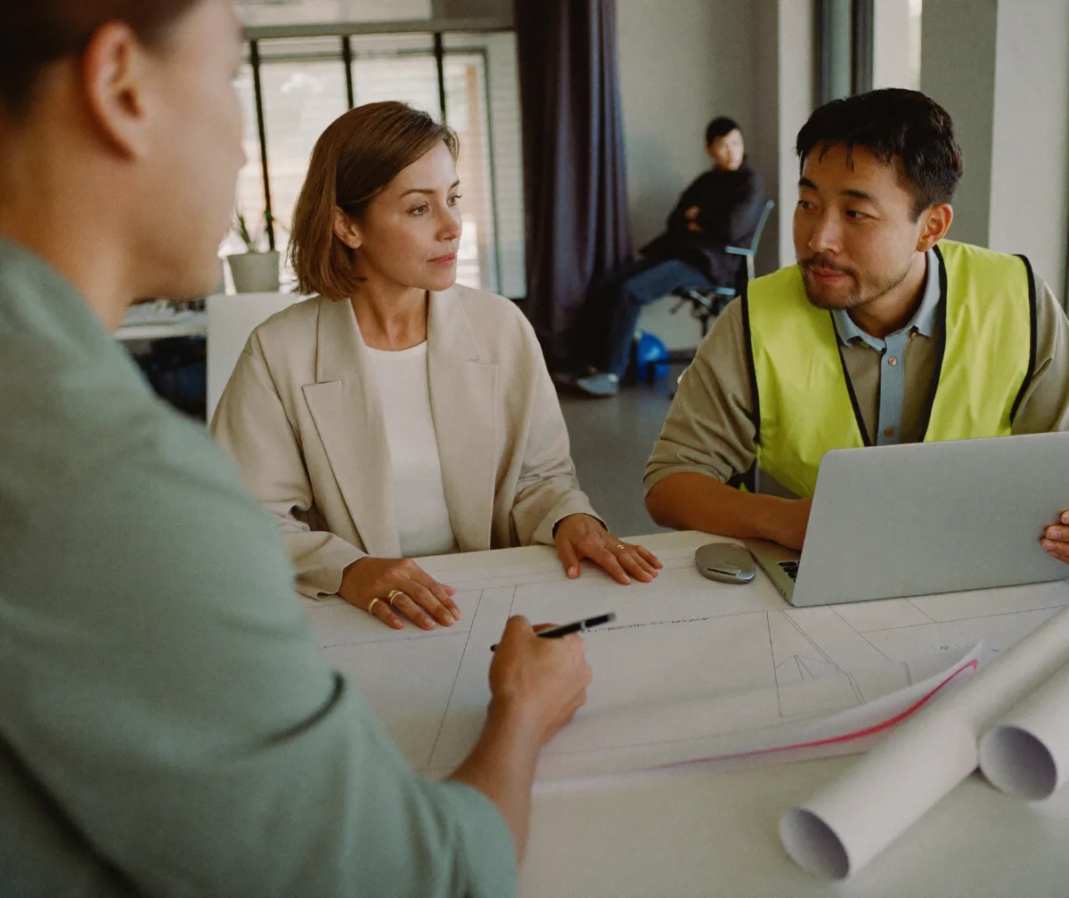 A construction company owner and project manager reviewing numbers with a finance advisor