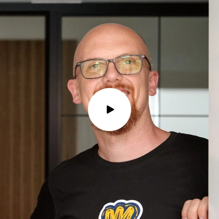 Lächelnder Mann mit weißen Hemd vor Laptops mit Website über Humanunternehmer.