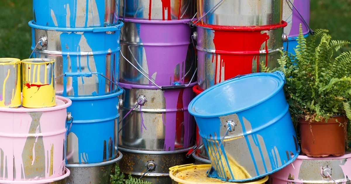The used paint cans. Many multi-colored buckets with traces of paint on them
