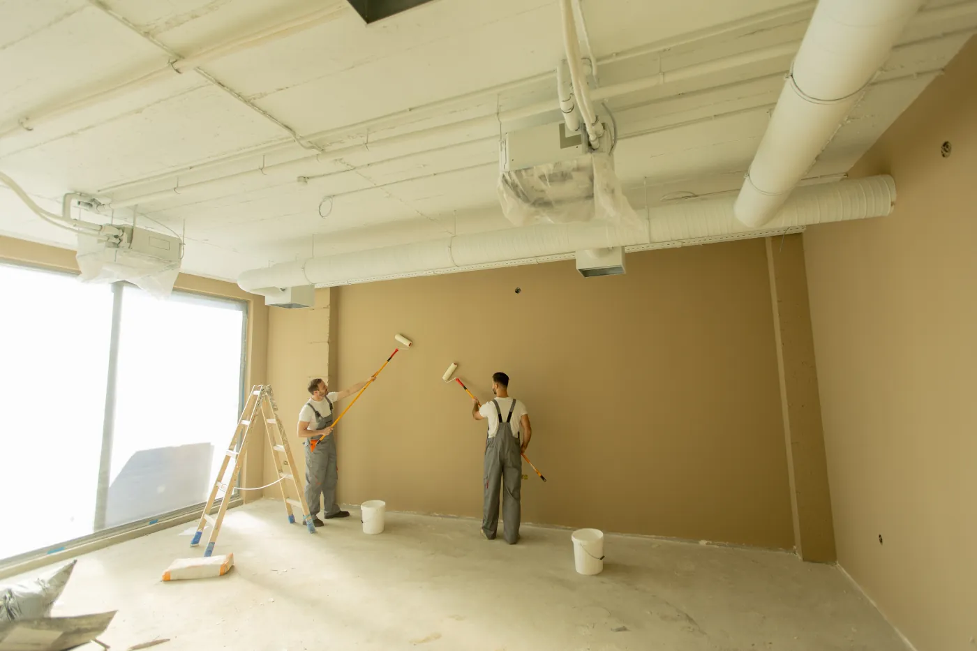 Two painting contractors working in an empty office space during a commercial interior painting project in Bellevue 