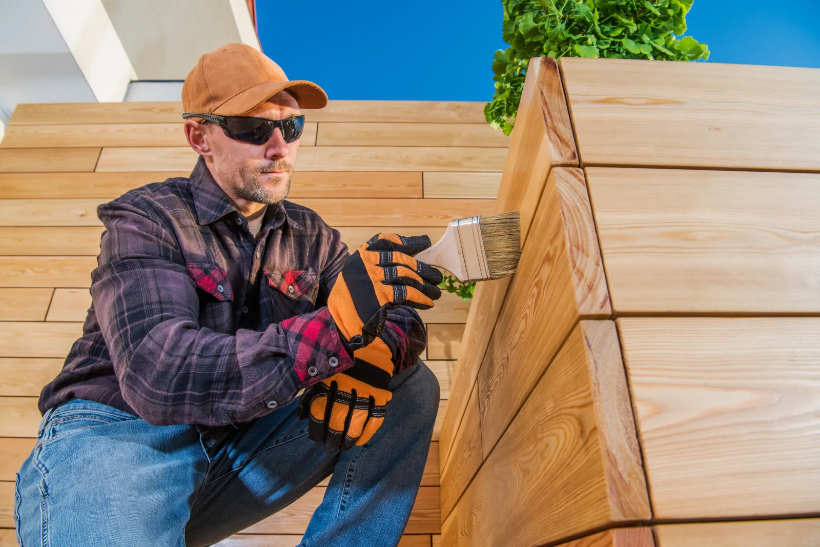 Professional painter applying semi-transparent stain to a cedar fence in Bellevue using a brush for even fence staining coverage