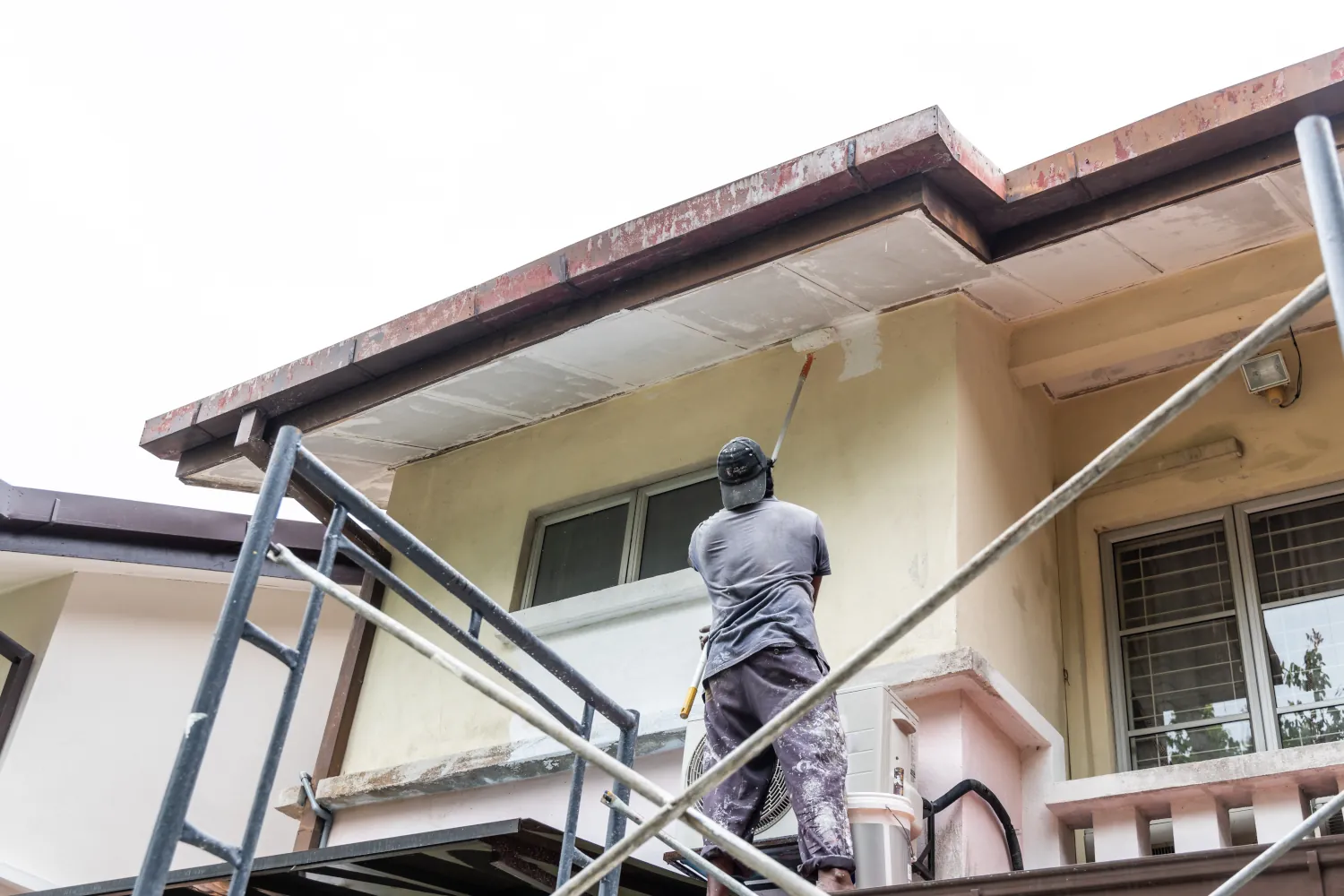 Professional painter applying acrylic paint to fascia and soffit on a two-story Bellevue home 