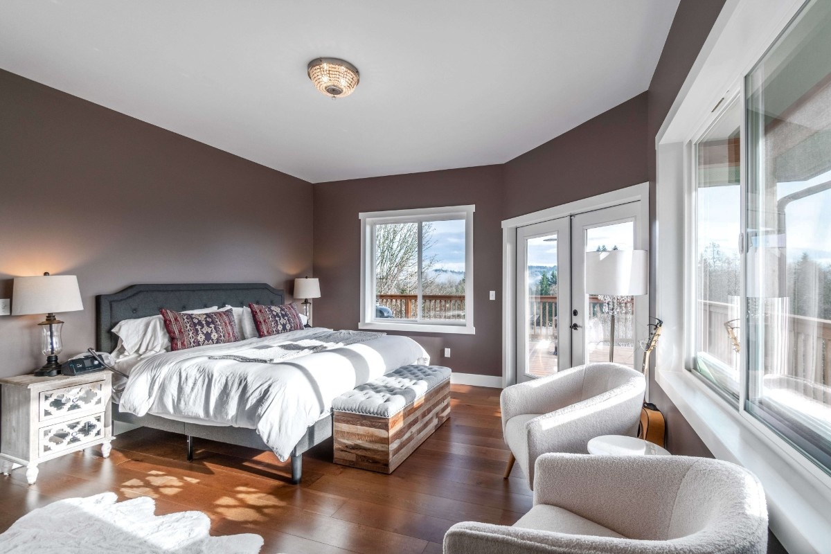 Bellevue primary bedroom with warm charcoal walls, white ceiling, and mountain view through French doors