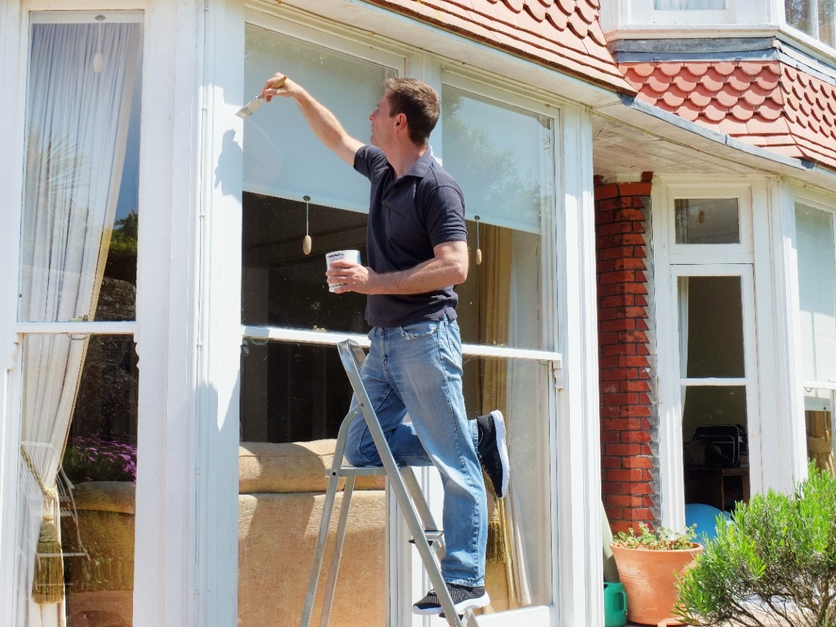 A painting contractor painting exterior of a pre-1970s home in Bellevue