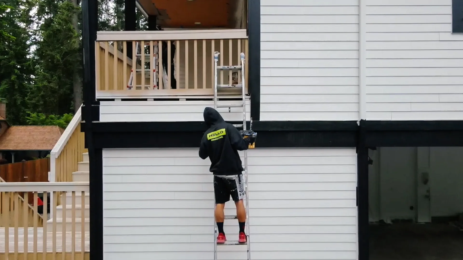 HELLO Painting crew member painting exterior siding on a residential home using a ladder during an exterior painting project