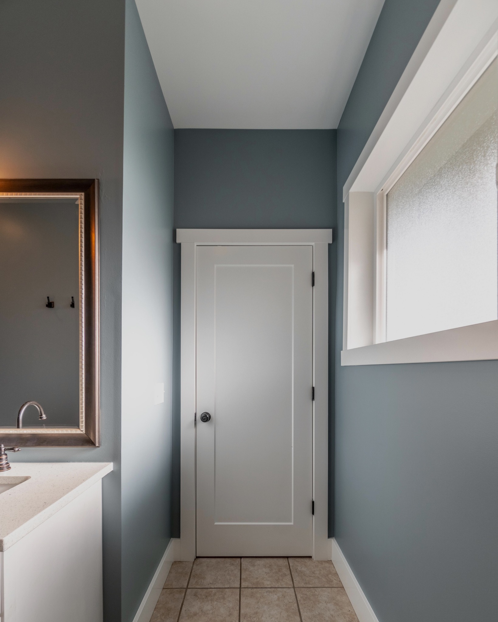 Freshly painted bathroom interior with soft blue walls, white trim, and door, showing a clean, modern finish after interior painting