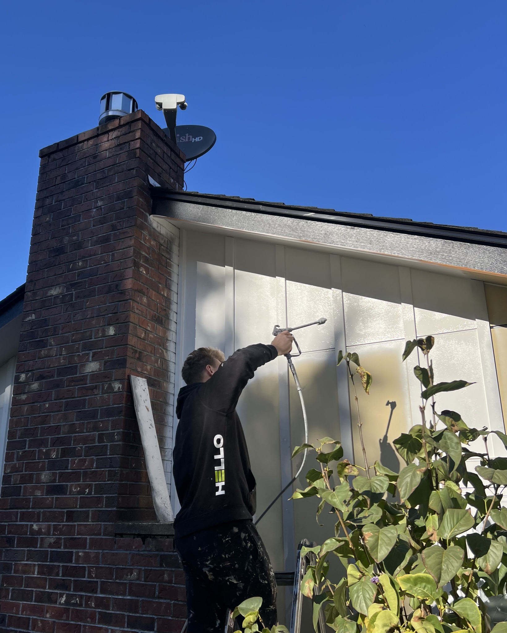 HELLO Painting crew member pressure washing exterior siding during prep work, removing loose paint and surface buildup before starting an exterior painting project