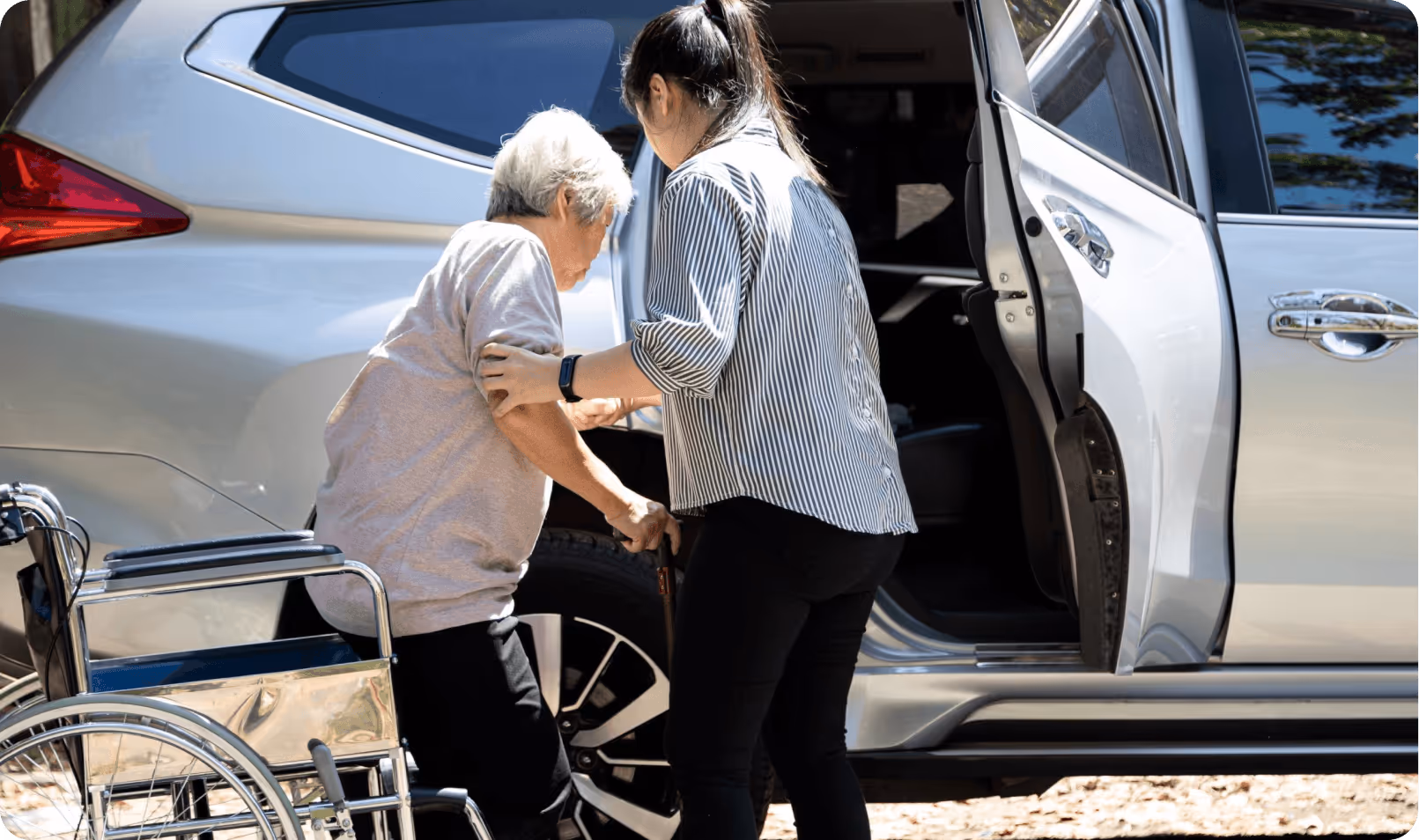 Caregiver assisting an older woman into a car for an ambulatory transportation service