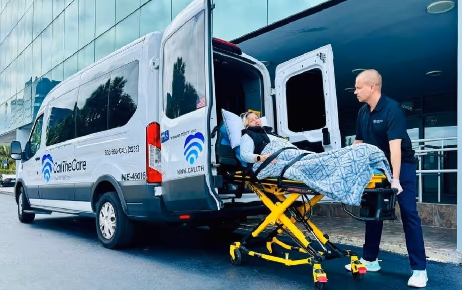 CallTheCare staff assisting a patient on a stretcher into a long-distance medical transport vehicle