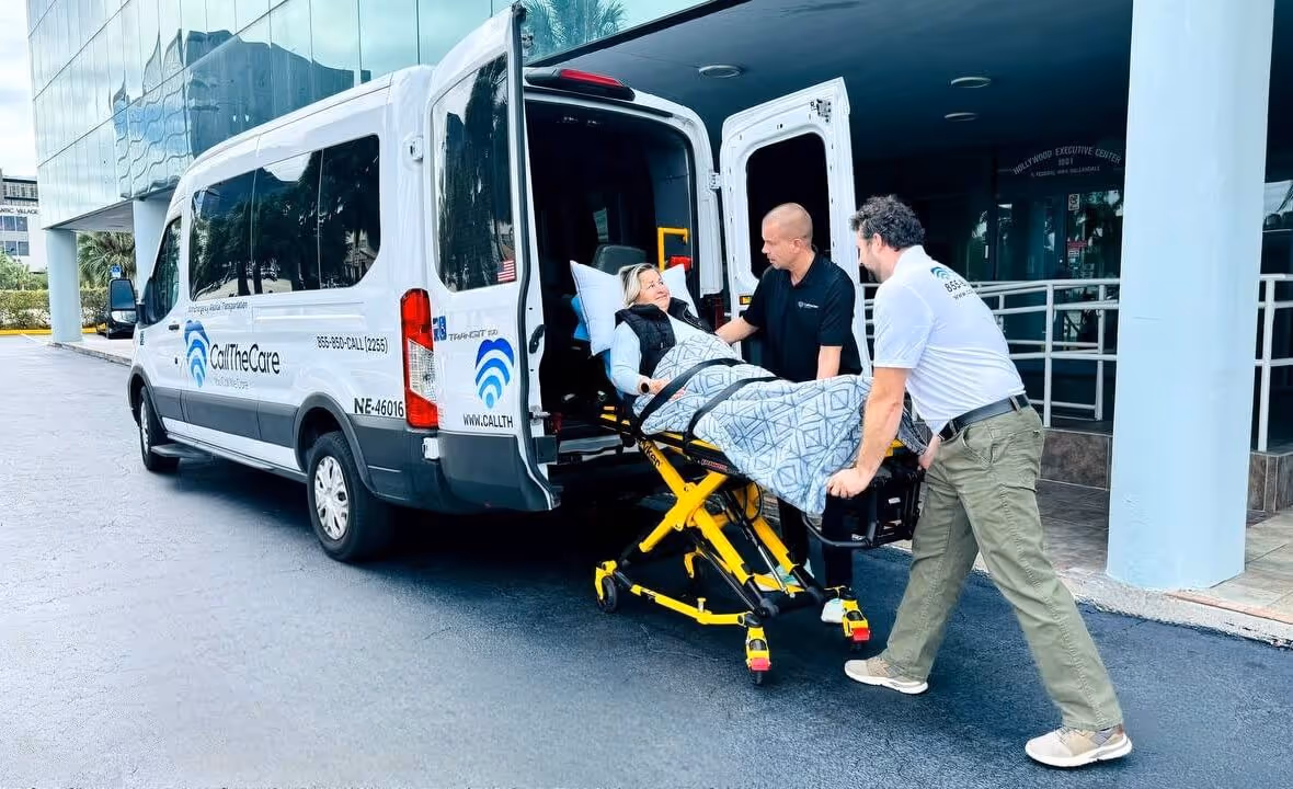 Two medical workers assist a patient on a gurney beside a CallTheCare van
