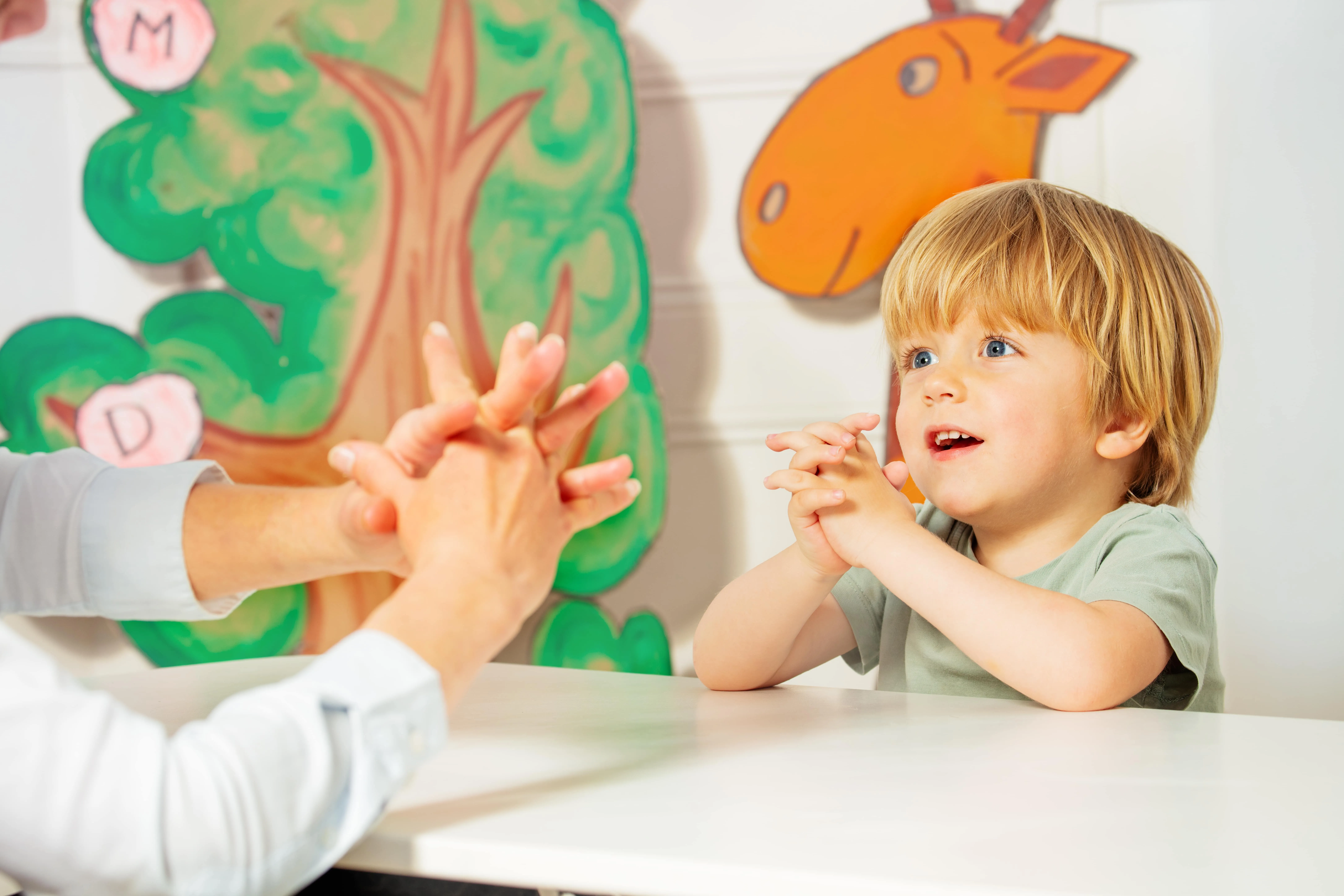 A child clasping their hands to imitate the therapist.