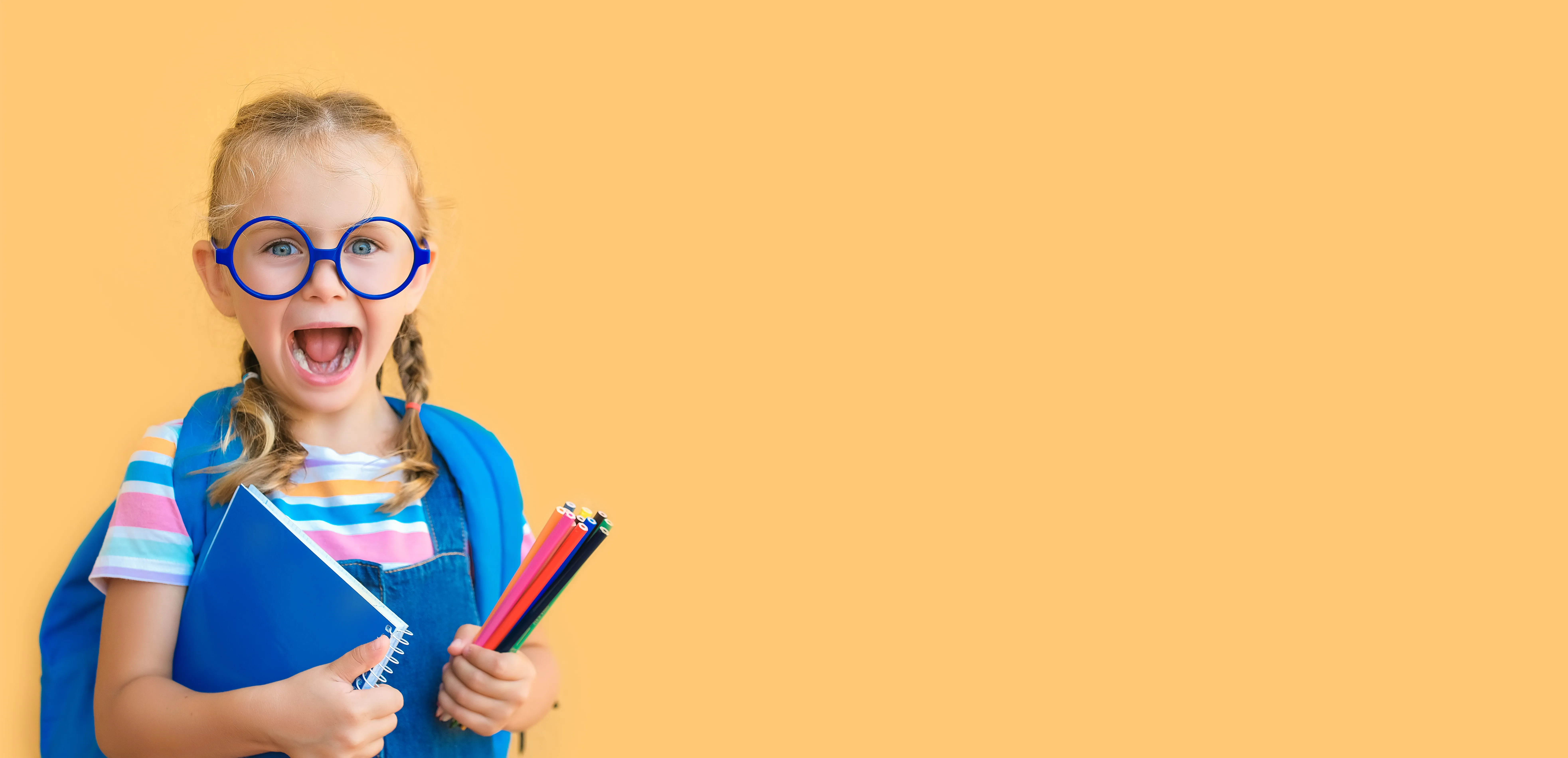 A smiling little girl with a book bag.