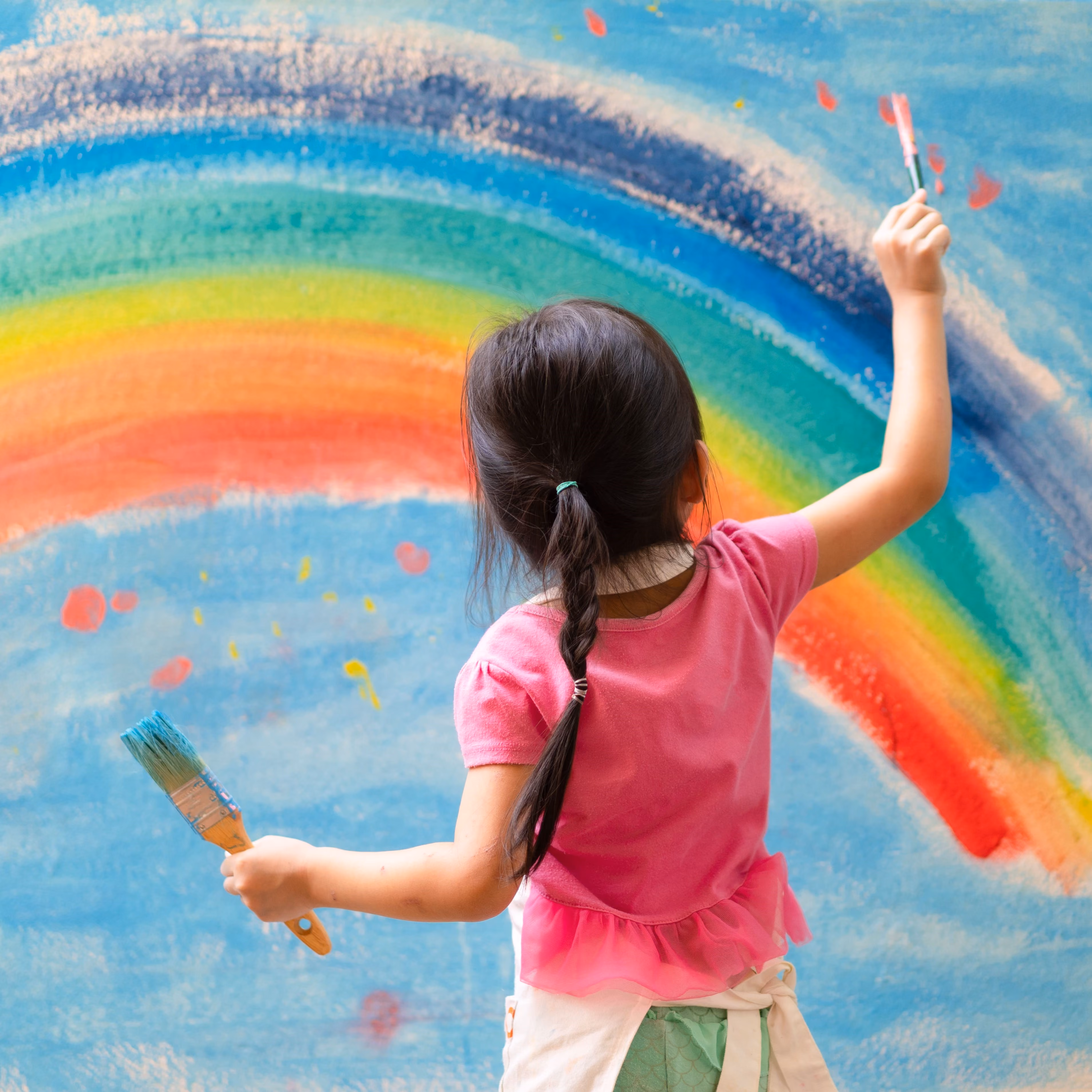A little girl painting a rainbow.