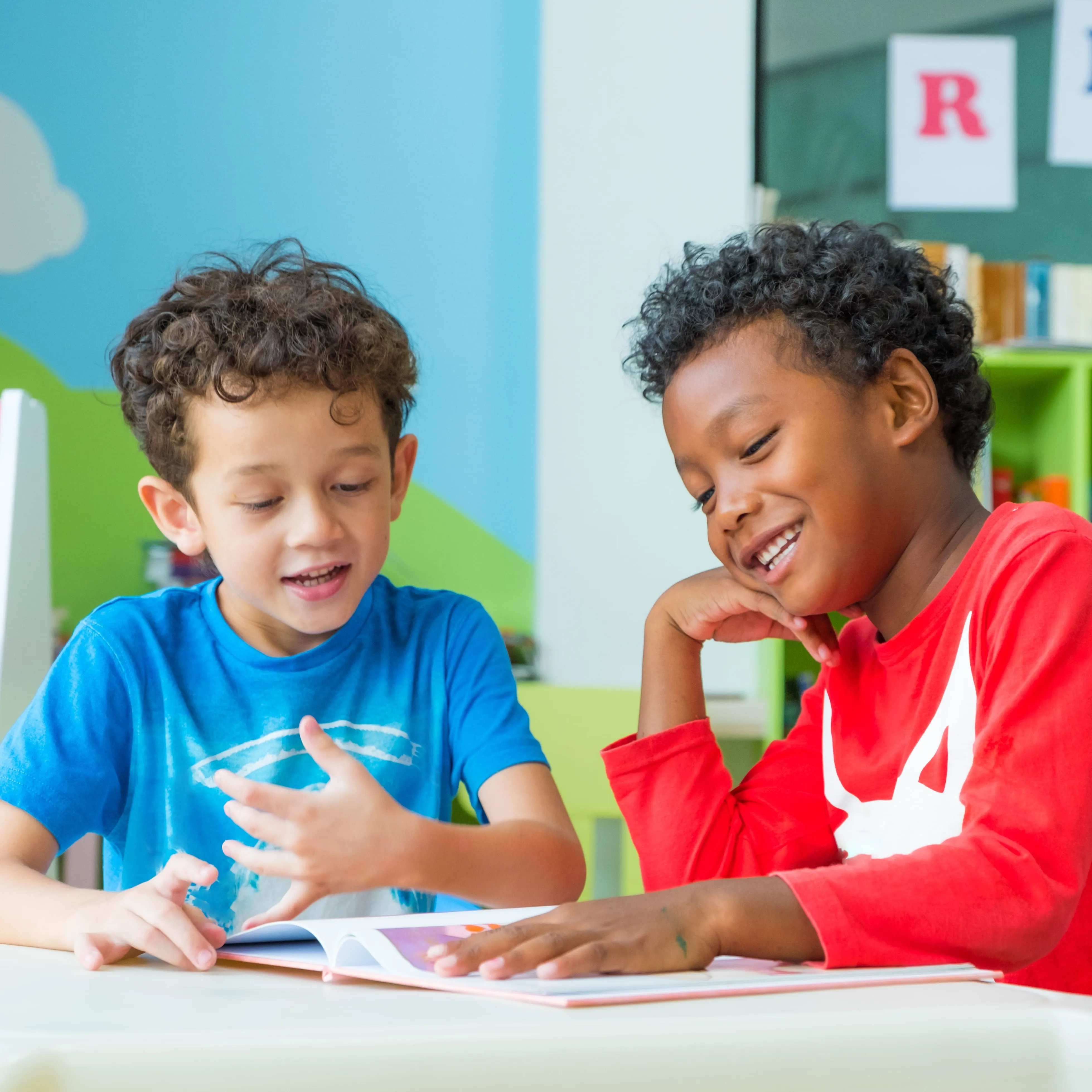 Two young boys reading a book.