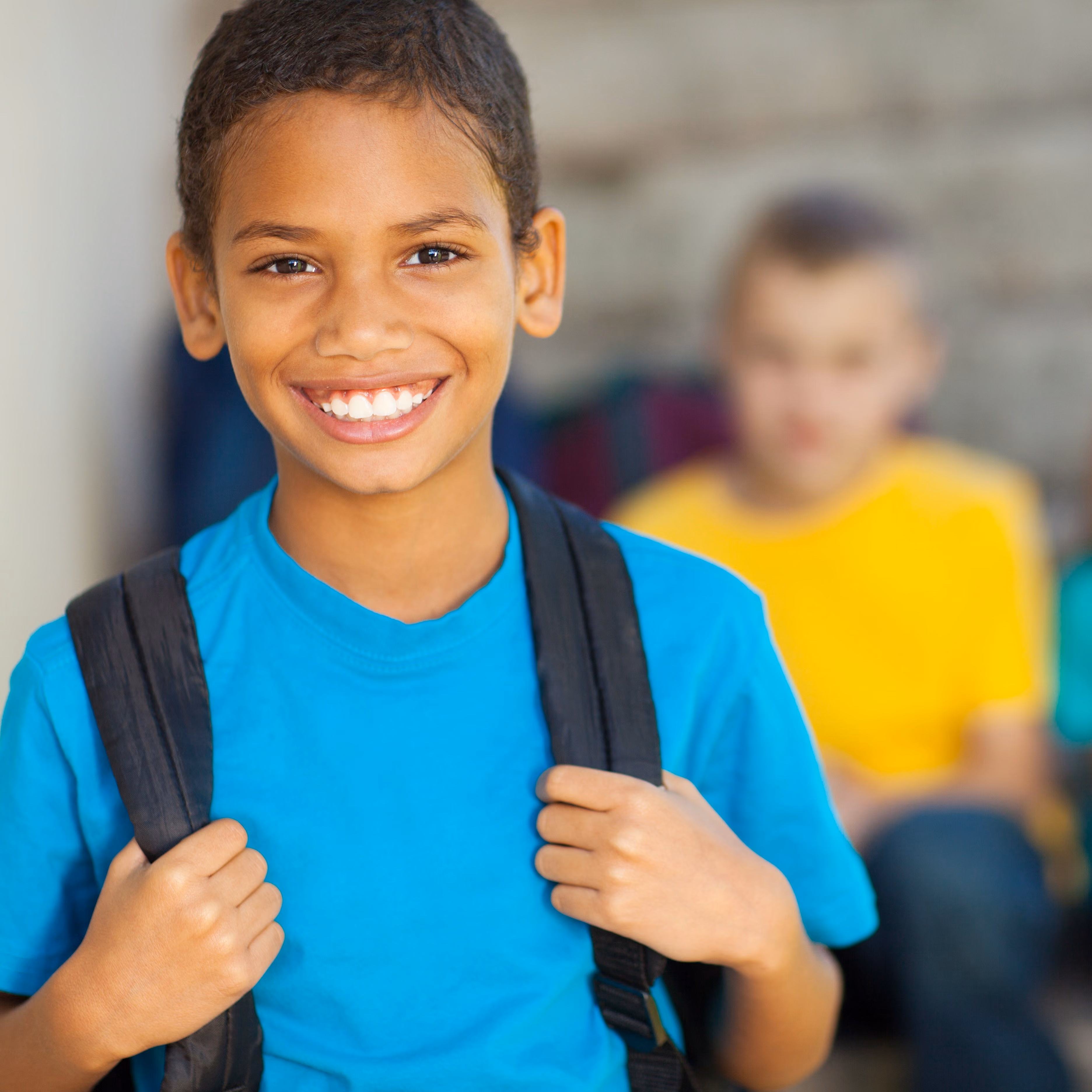 A student with his bookbag and peers in the background.