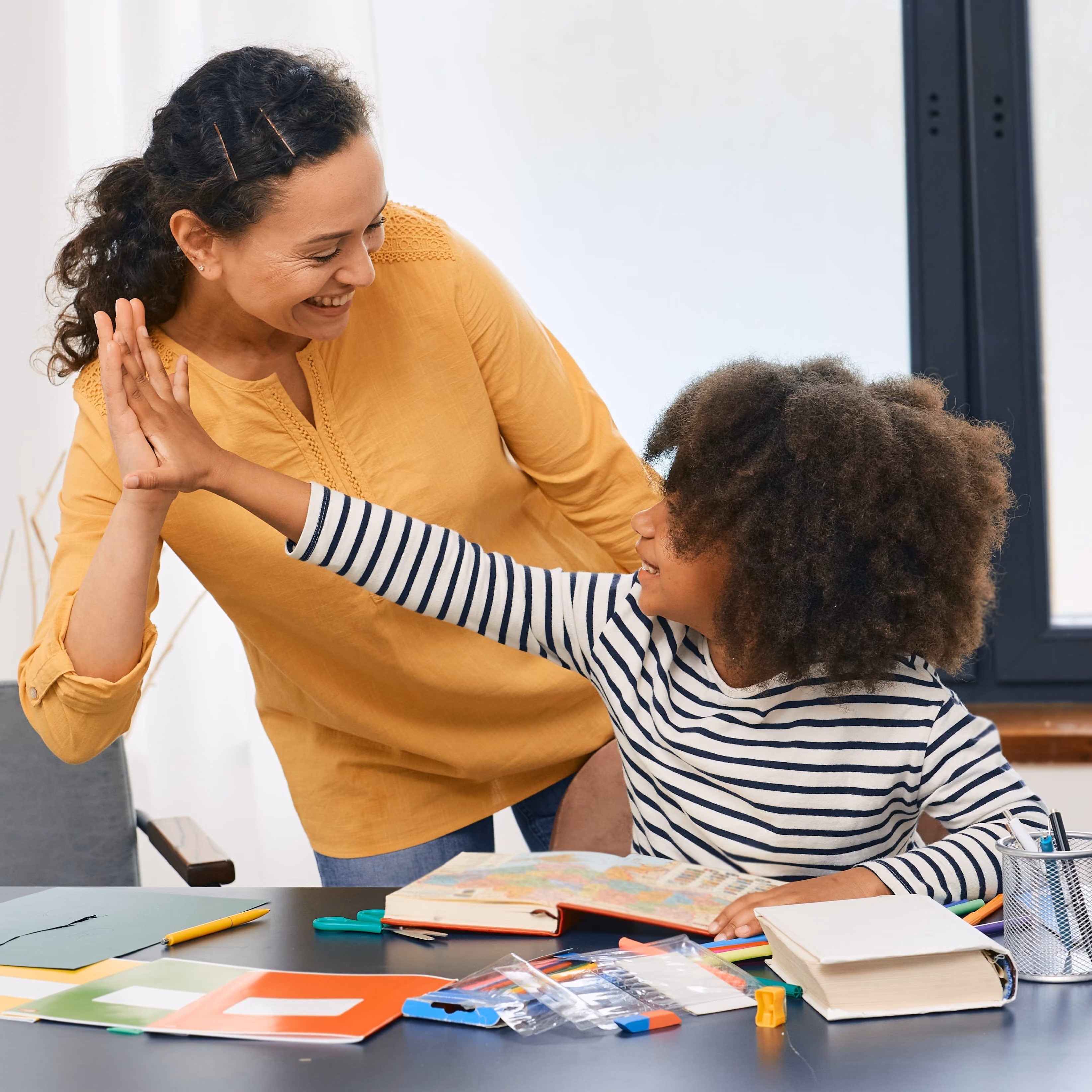 A mother and daughter high-fiving while working on homework.
