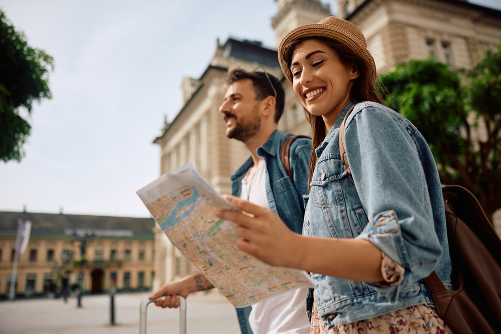 A couple walking on holiday in a foreign city. The woman is looking down at a map.
