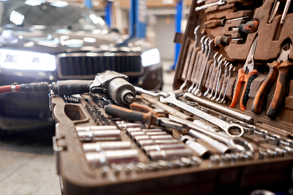 A close up of a mechanics tool box with a car in the background. The tools are used as a metaphor for digital tools. 