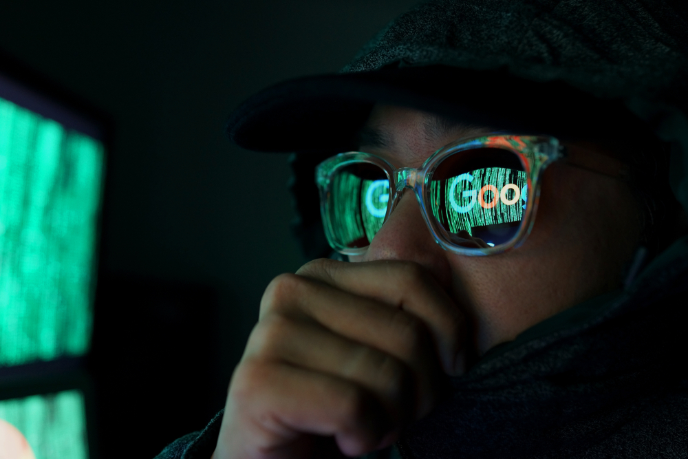 A person's face covered with glasses reflecting digital code with Google written on the screen.
