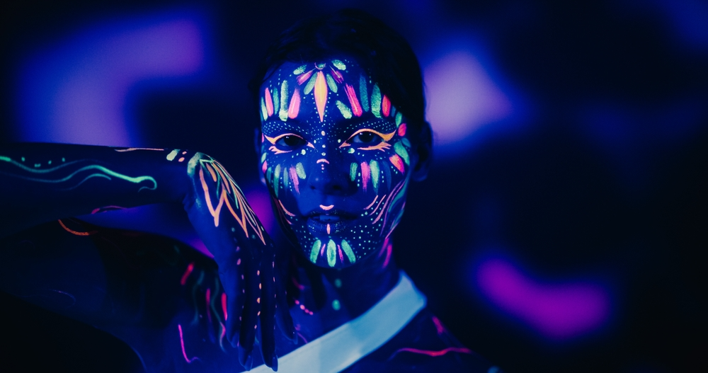 A dancer with neon glowing paint on her face. 