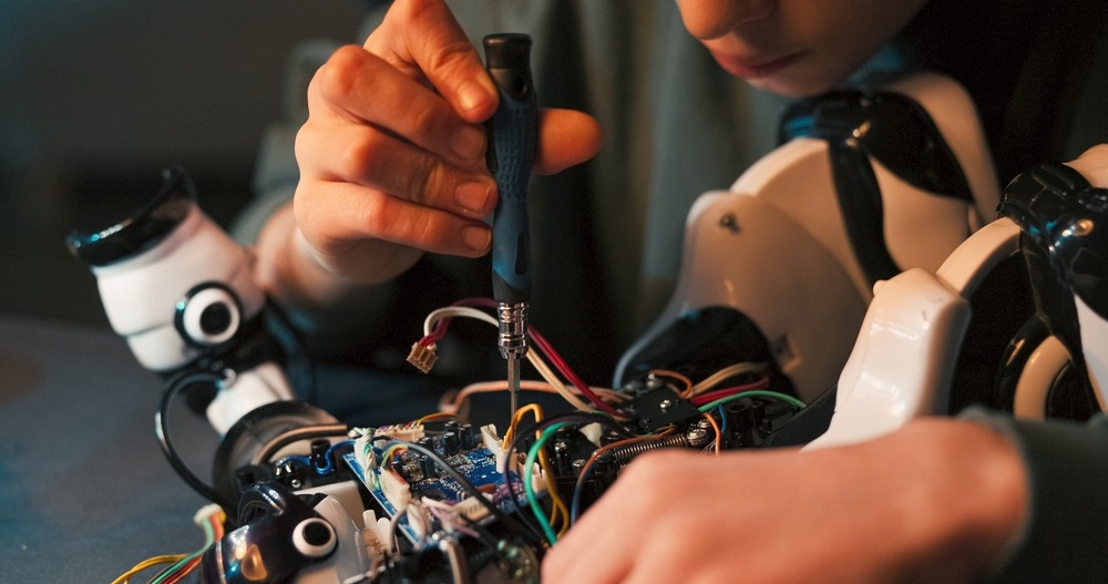 A person working on the wires of a robot.