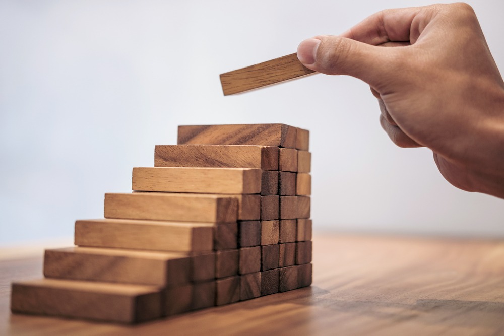 A hand building a staircase out of blocks.