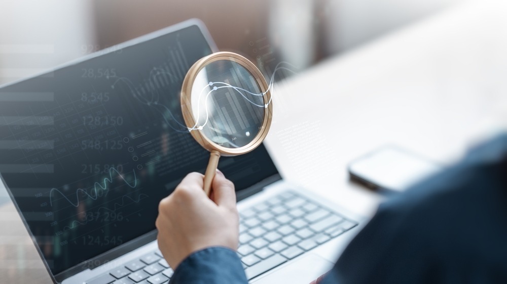 A magnifying glass in front of a computer displaying analytics. 