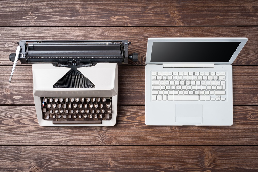A typewriter and laptop next to each other displaying the evolution of search and content.