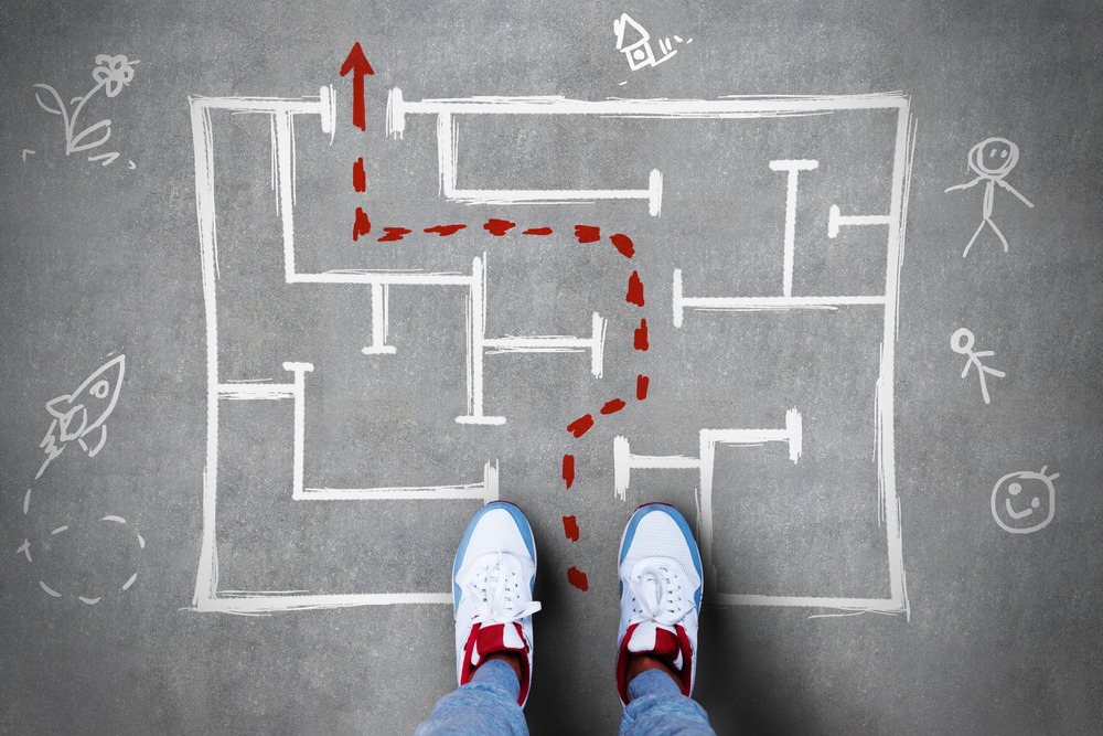 Two feeting standing at the start of a drawn maze graphic with a dotted line showing the path through.