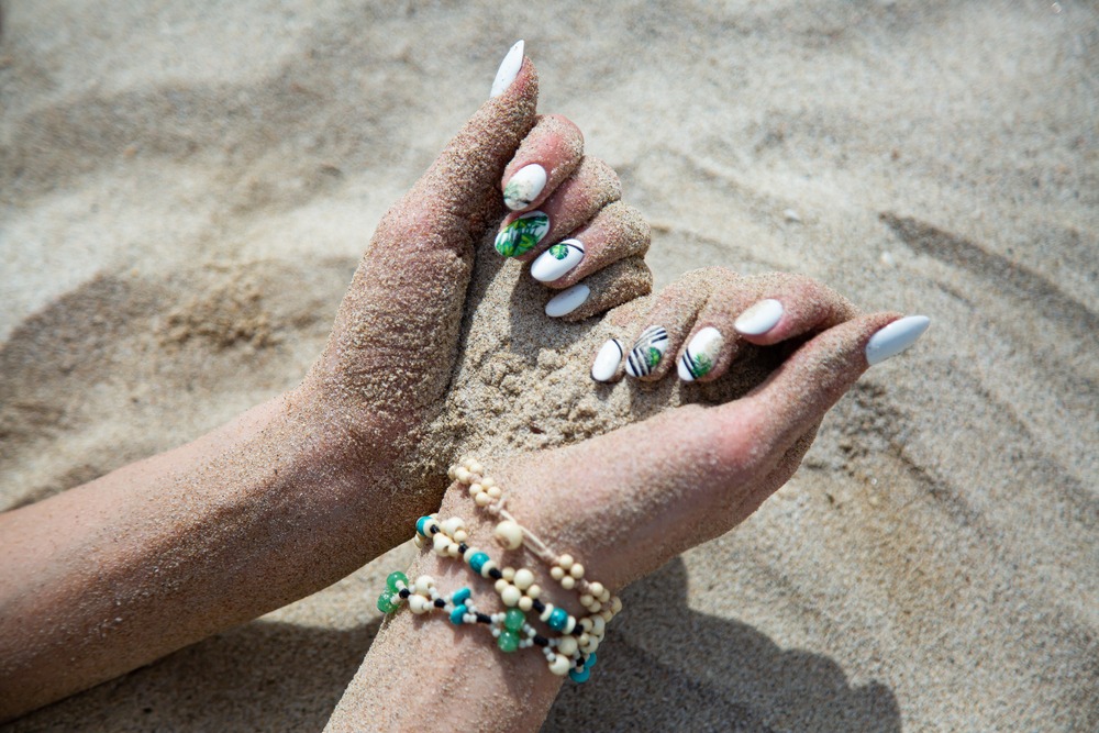 A woman's hands scooping up sand. A feel that most Australian's can relate to creating a sense of sensory branding. An image you can feel, smell, and even hear.