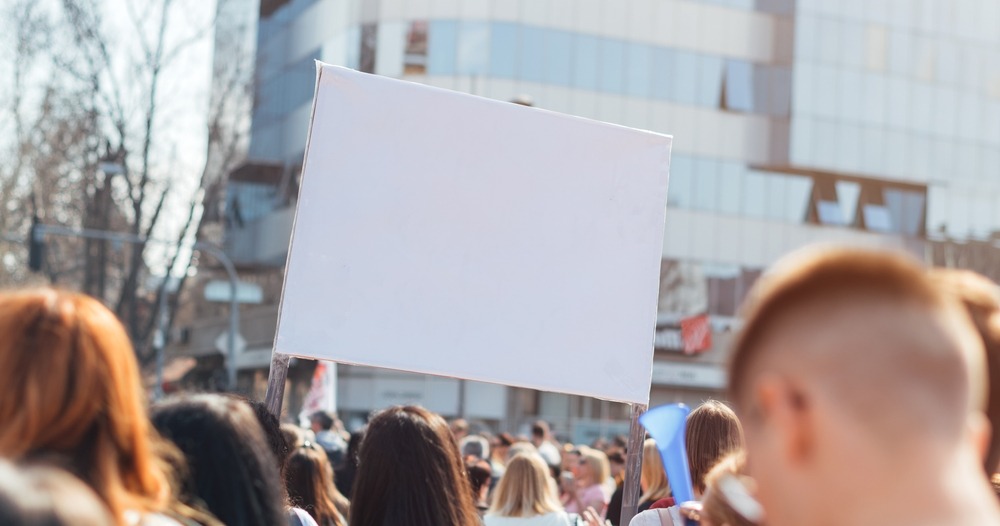 A group of people advocating in the city holding a blank sign. A representation of how retention marketing strategies turn people into brand advocates.