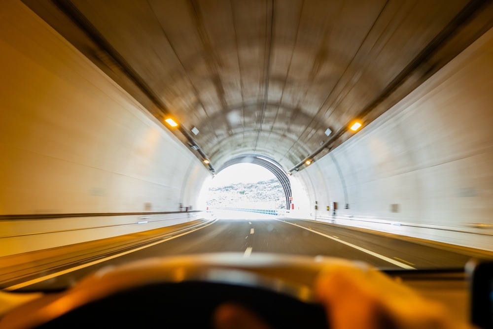A view from a person driving a car looking out towards the road about to reach the end of a tunnel. A metaphor for the customer journey not ending at the checkout.  