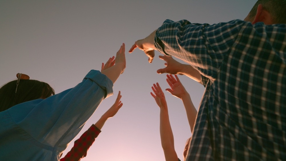 A group of people with their hands raised to the sky indication they focusing on human-led content marketing. 