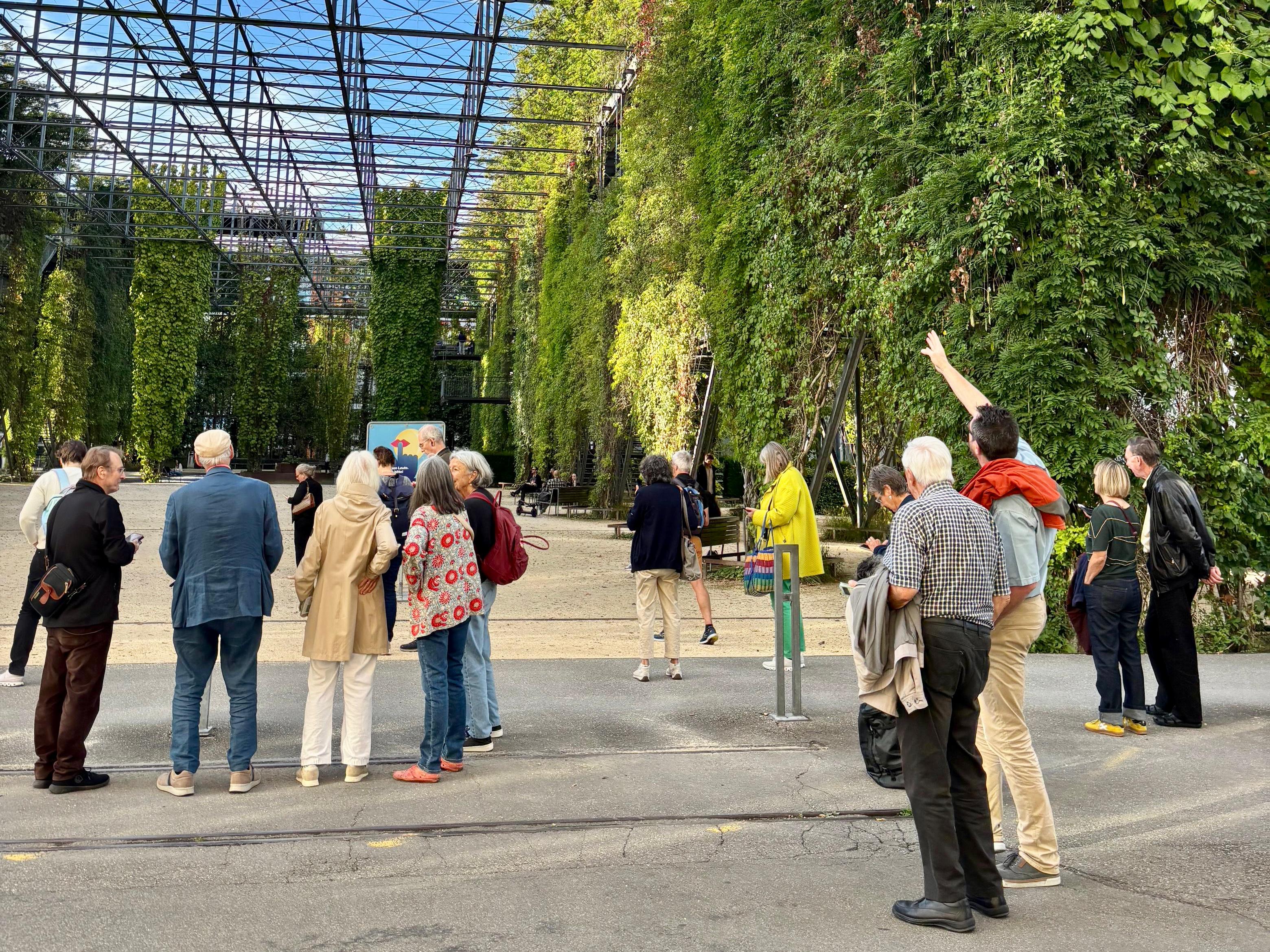 Die Gäste der Eröffnungsfeier stehen mit ihren Handys in der Hand im MFO-Park, der mit grünen Kletterpflanzen bewachsen ist, und testen die neue doyo-Tour.