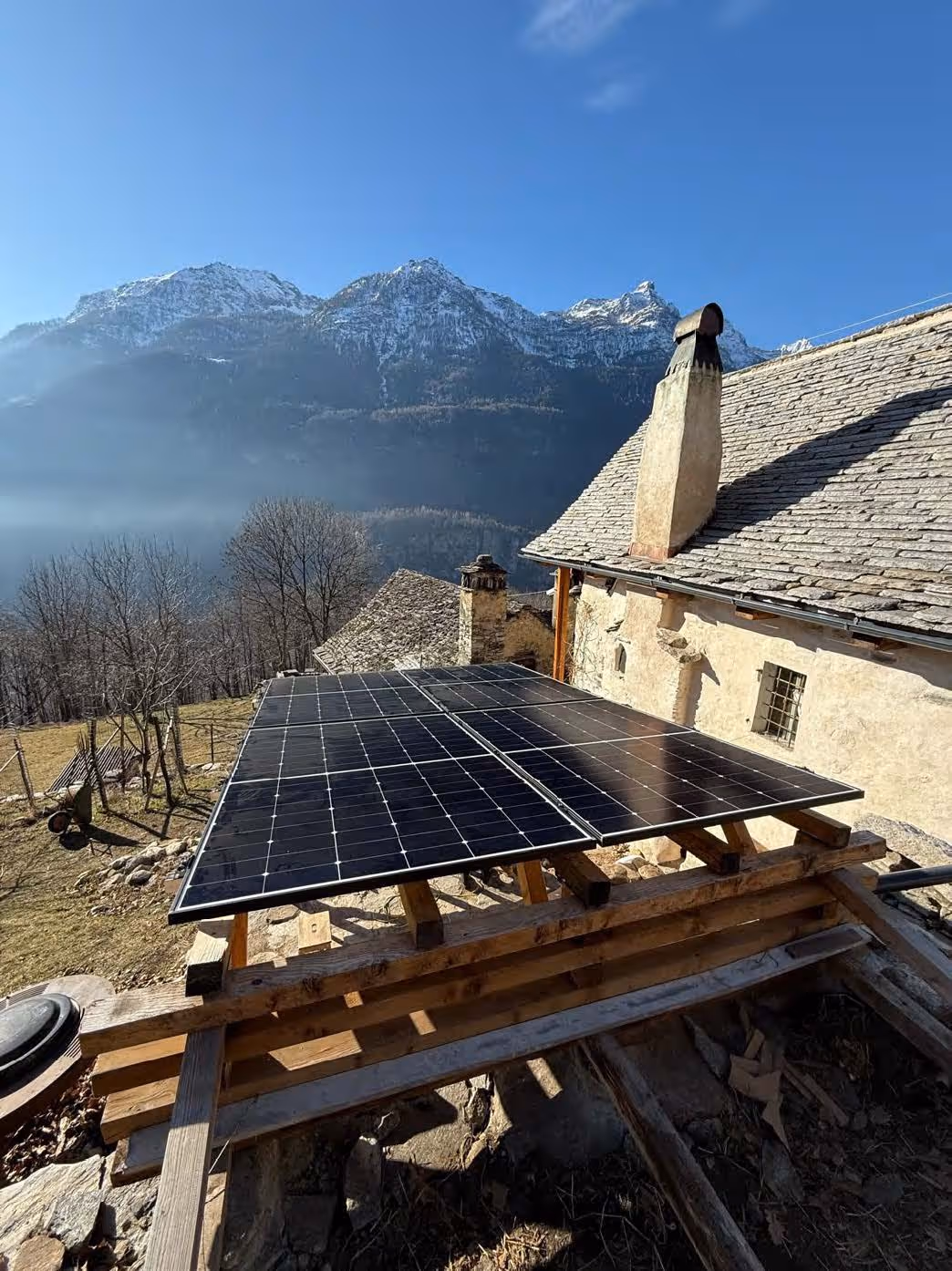 Landschaftsfoto aus Luftperspektive, zeigt vier Mehrfamilienhäuser mit Solaranlagen auf den Flachdächern, im Hintergrund Thunersee und Bergpanorama.
