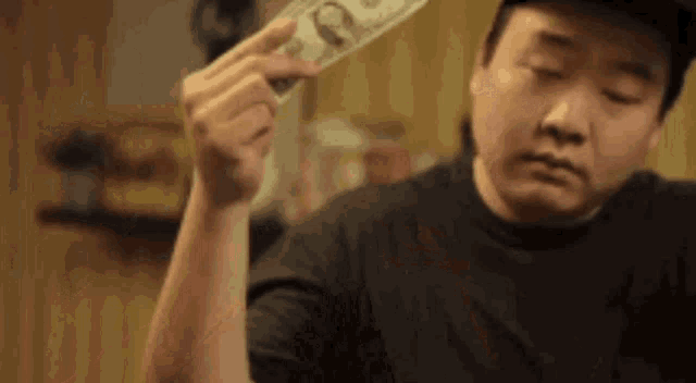 A man is holding a dollar bill in his hand and dances with it. Then he shoots the dollar out of his hand. A parody of throwing lots of bills around. 