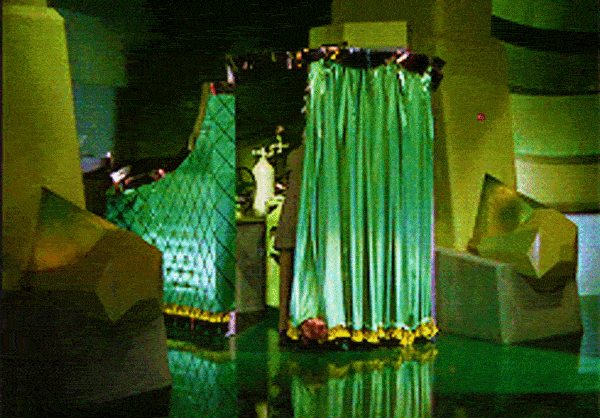 The Wizard of Oz: A man is behind a green curtain working a large contraption. Toto the dog pulls the curtain away to reveal the man.