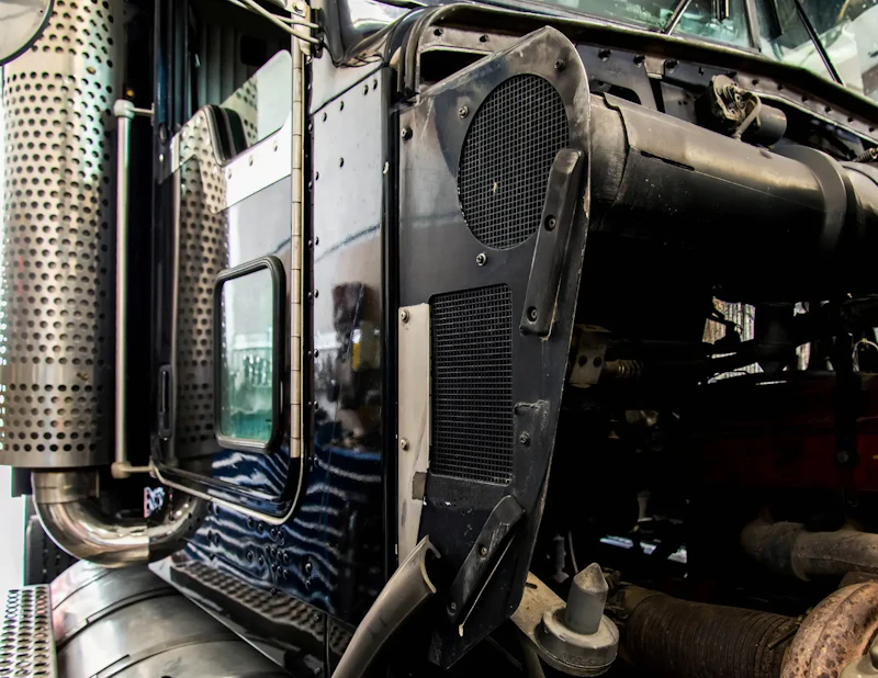 Semi-truck engine compartment open during diesel repair, showing intake housing, exhaust stack, and exposed engine components.