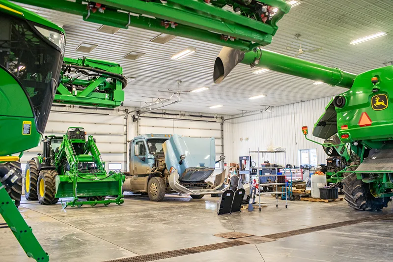 Western Illinois harvest season service with agricultural equipment and a heavy-duty truck in a repair shop.