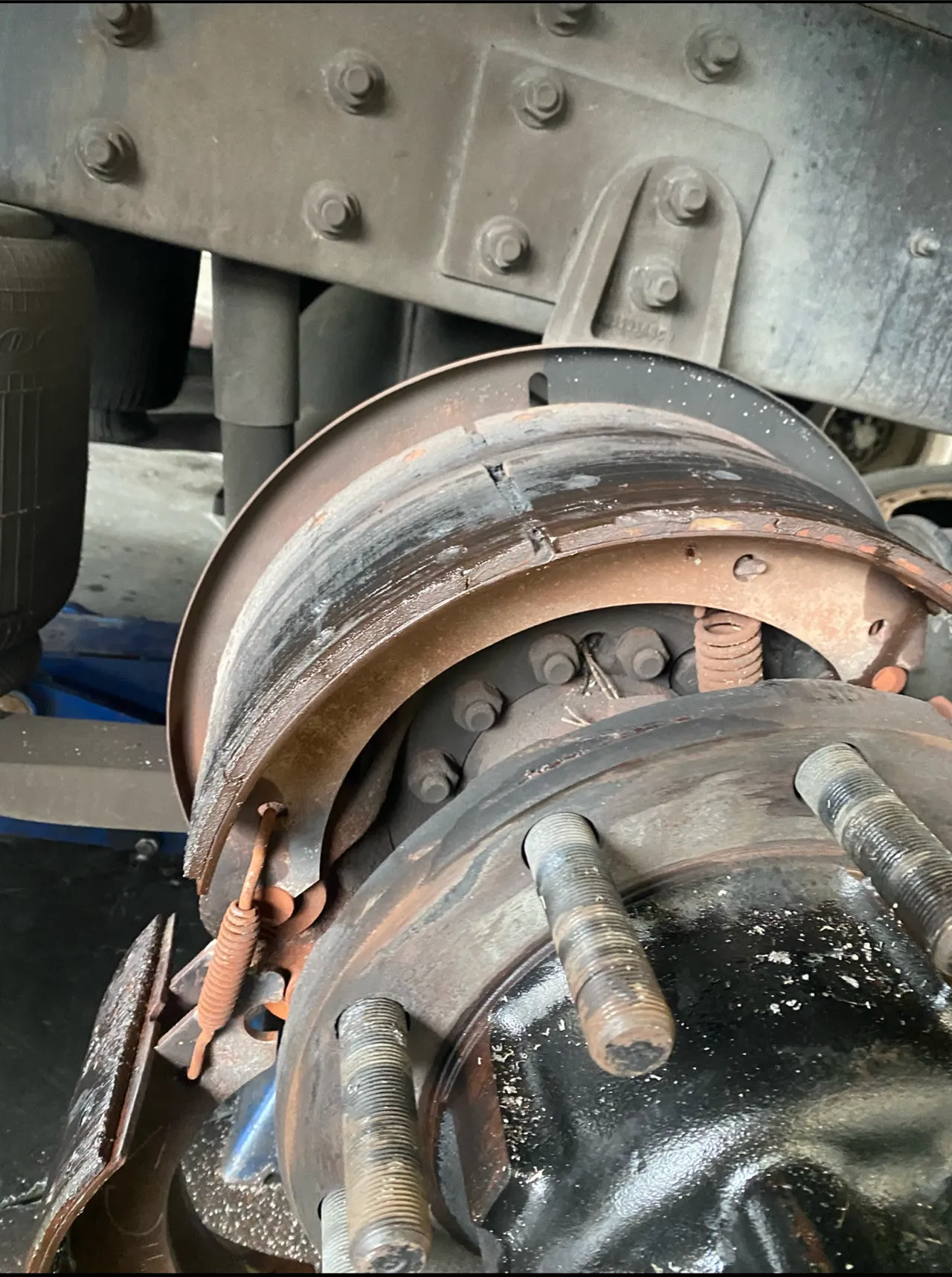 Close-up of a heavy-duty truck drum brake assembly showing a cracked and worn brake shoe lining during inspection.