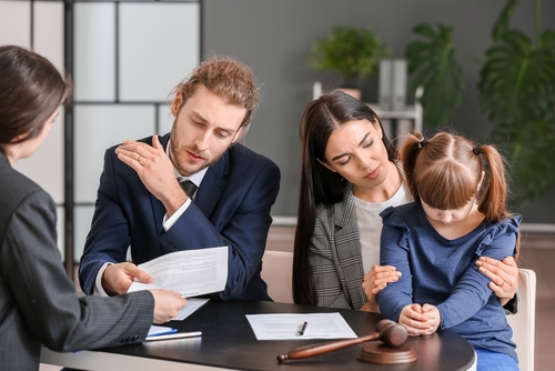 Family with a child consulting a teacher and coach sexual abuse lawyer in an office, illustrating when you may need an attorney for a school abuse claim.
