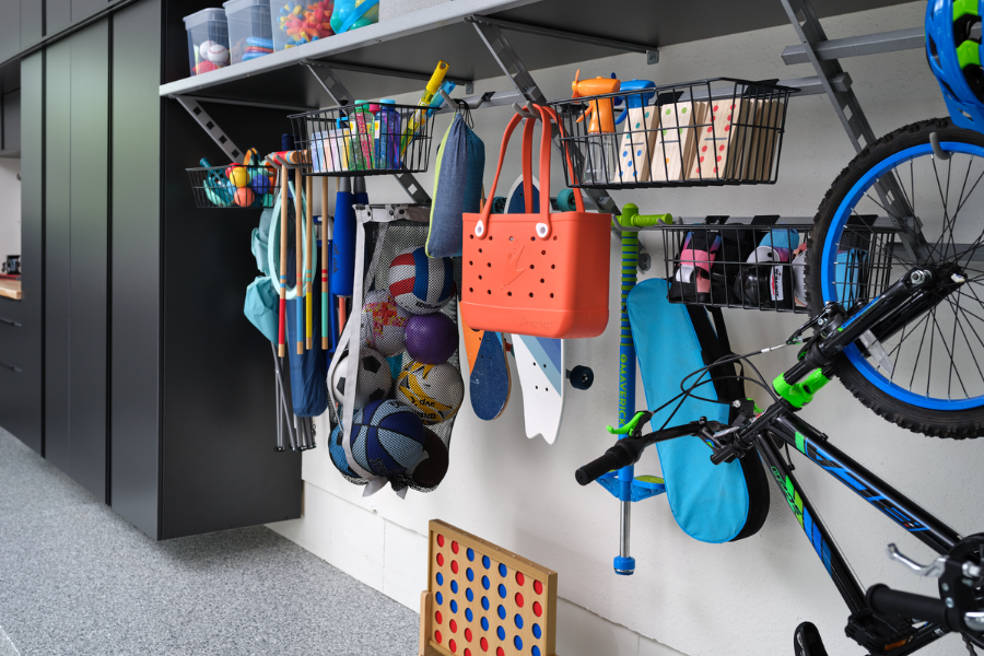 Garage wall storage with baskets, bins, hooks, and racks holding sports gear, toys, bikes, and outdoor accessories in an organized layout.