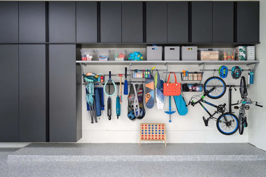 Modern garage storage system with overhead cabinets, open shelving, and wall-mounted racks holding bikes, sports equipment, and storage bins.