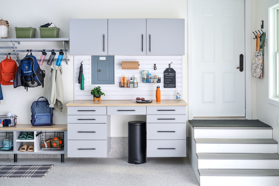 Organized mudroom and garage entryway featuring custom storage cabinets, slatwall organization, bench seating, and built-in storage for backpacks, shoes, and household essentials.