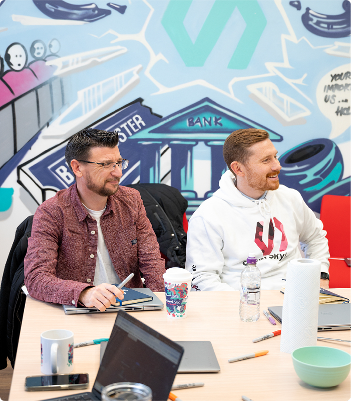 Team members in a workshop with creative mural artwork in the background.