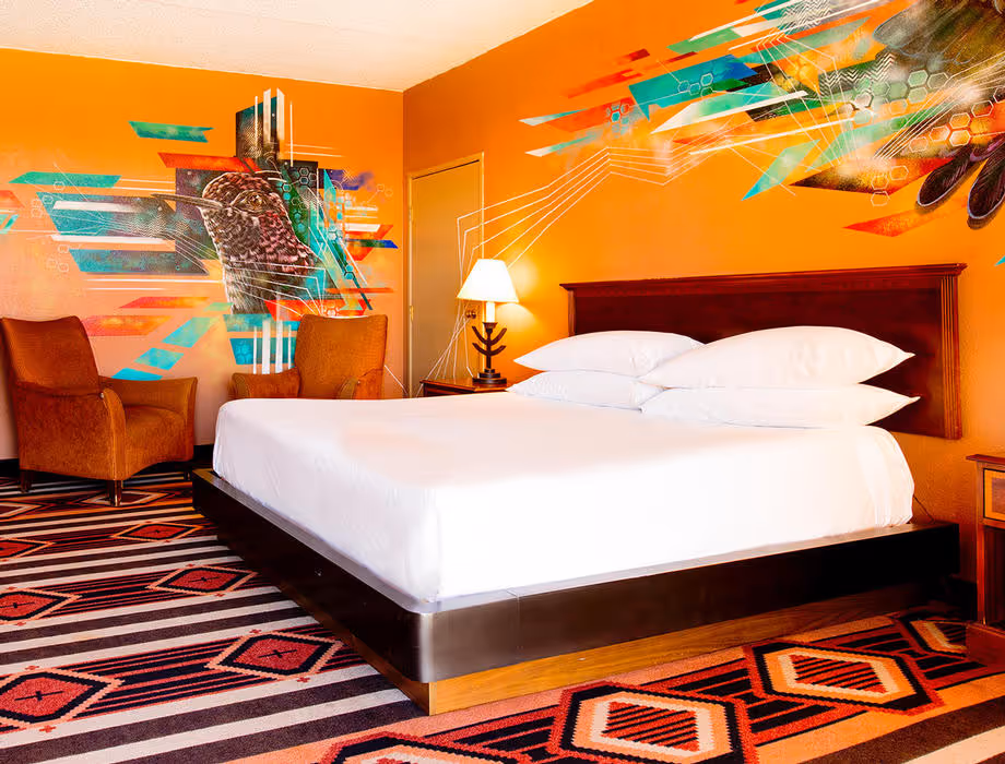 Colorful Artist guestroom with mural on the wall with king bed with white bedding