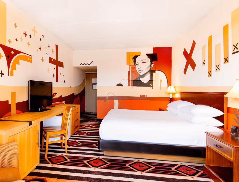 Colorful Artist guestroom with mural on the wall with king bed with white bedding