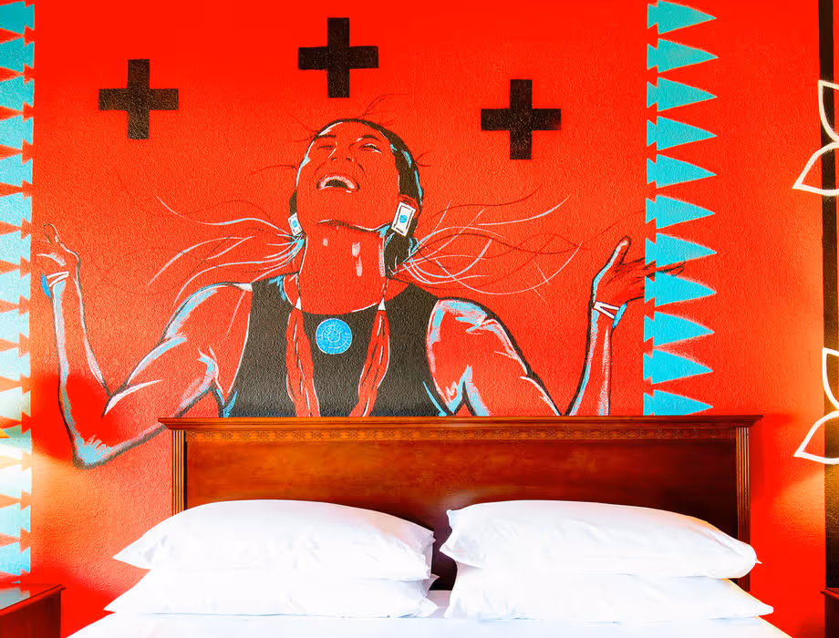 Colorful Artist guestroom with mural on the wall with king bed with white bedding